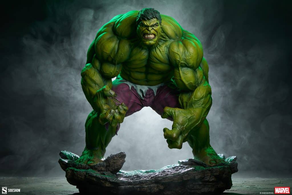 A highly detailed statue of the Hulk, featuring his muscular green form in an aggressive pose, standing on a rocky base with smoke in the background.