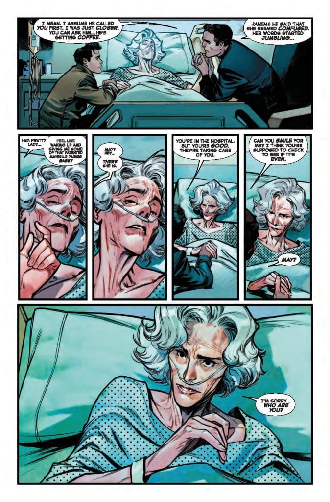 A woman with silver hair lies in a hospital bed, wearing a hospital gown and oxygen mask, while two men are engaging with her. One man leans forward, expressing concern, while the other sits close, trying to reassure her. The woman appears confused and asks who they are.