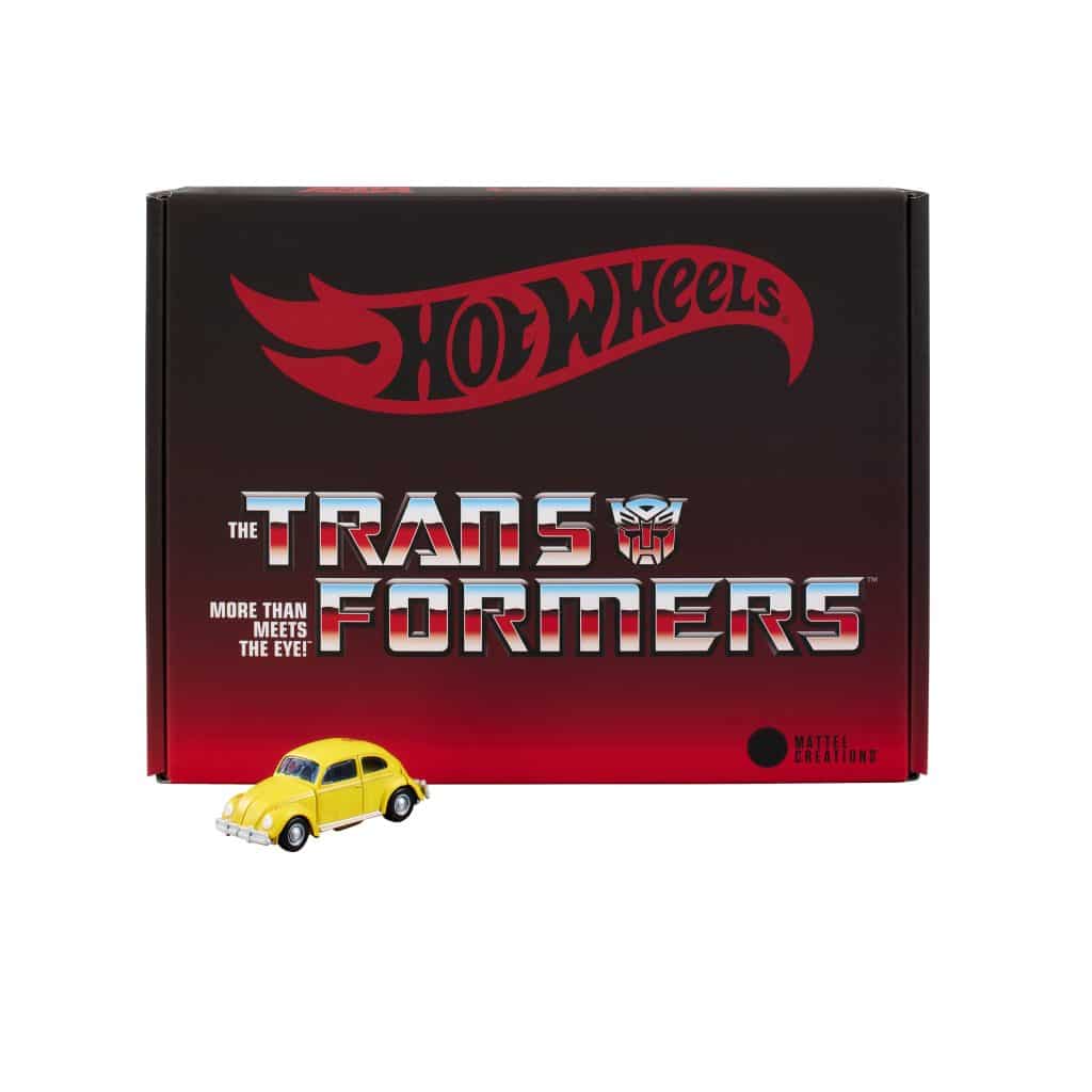 A yellow Hot Wheels toy car positioned next to a black and red box featuring the Transformers logo and branding.