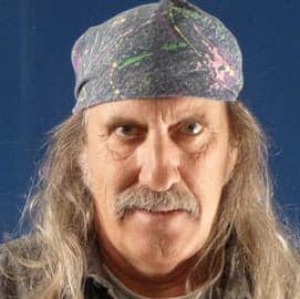 Portrait of a man with long hair and a colorful bandana, looking directly at the camera.