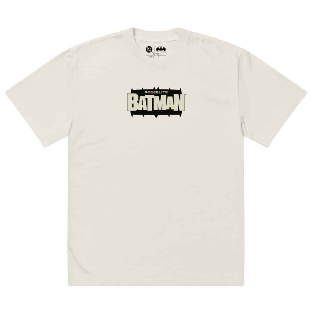 A light-colored t-shirt featuring the text 'ABSOLUTE BATMAN' in bold, black letters with a decorative design.