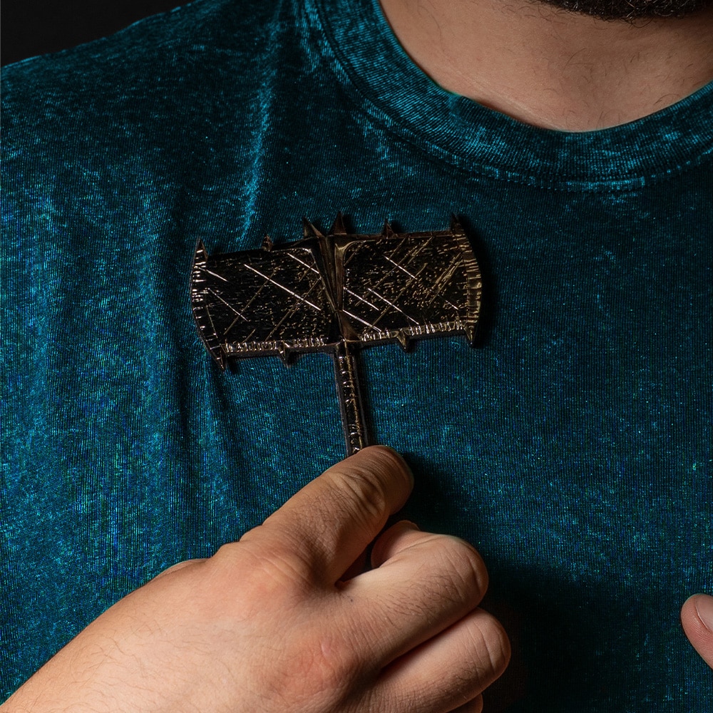 A person holding a double-headed axe prop against a textured blue-green shirt.