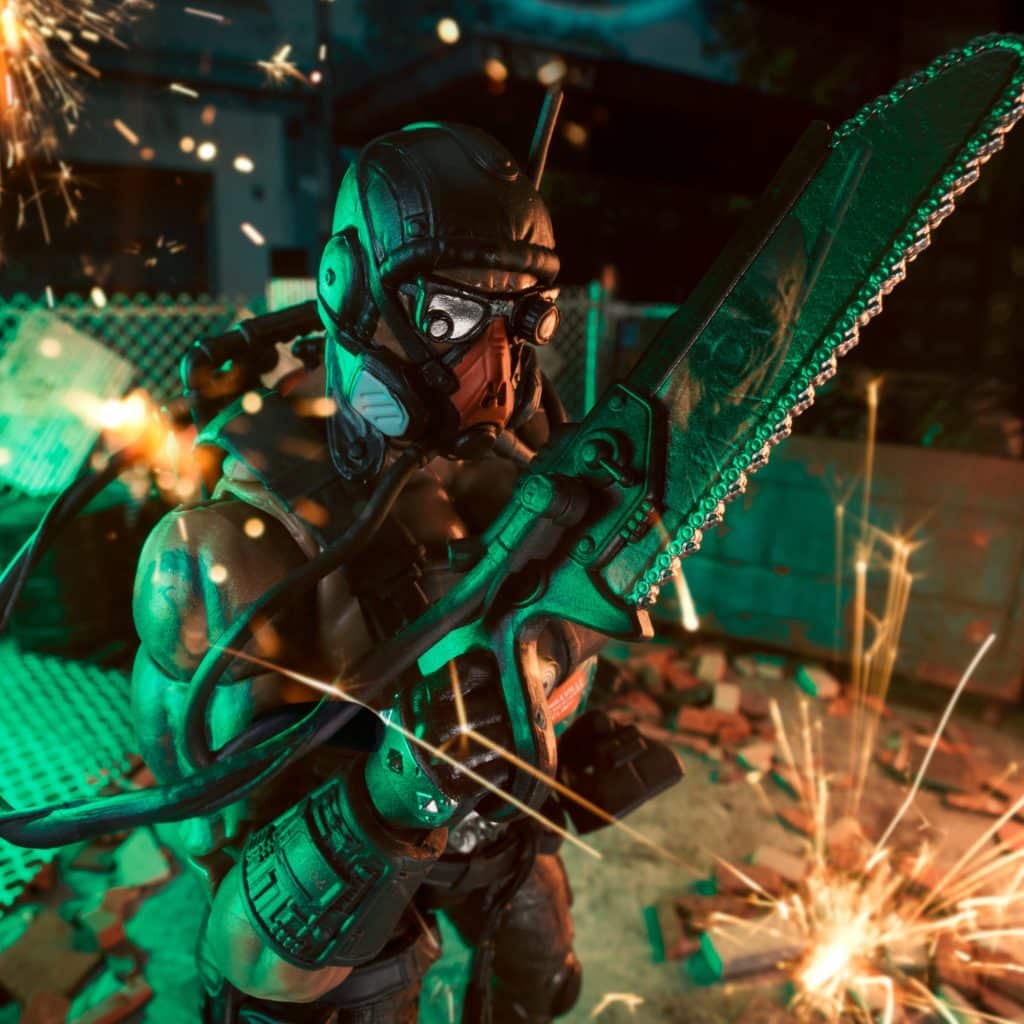 A stylized action figure of a soldier holding a chainsaw, depicted in a dynamic pose with sparks flying around, set against a gritty, urban background.