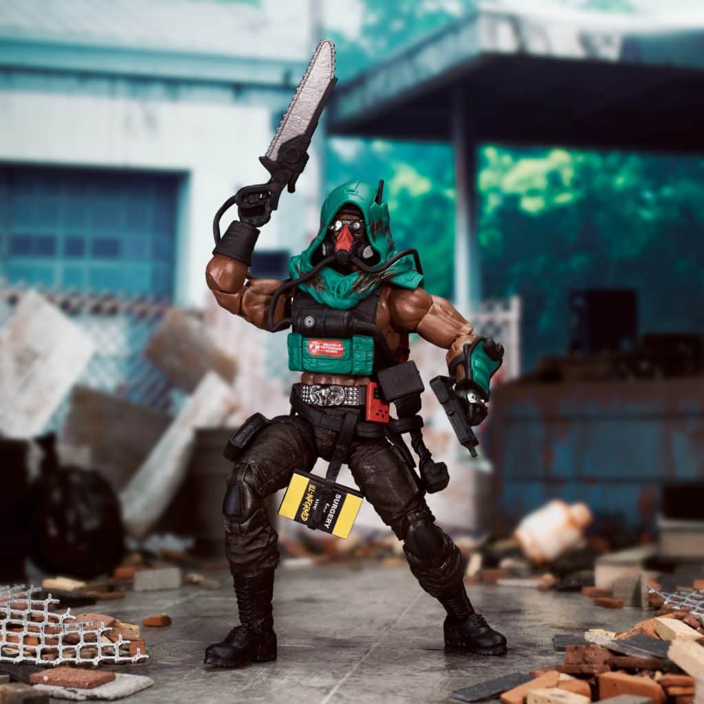 Action figure of a muscular character wielding a chainsaw and a handgun, dressed in tactical gear with a hood, standing amid an urban debris-filled environment.