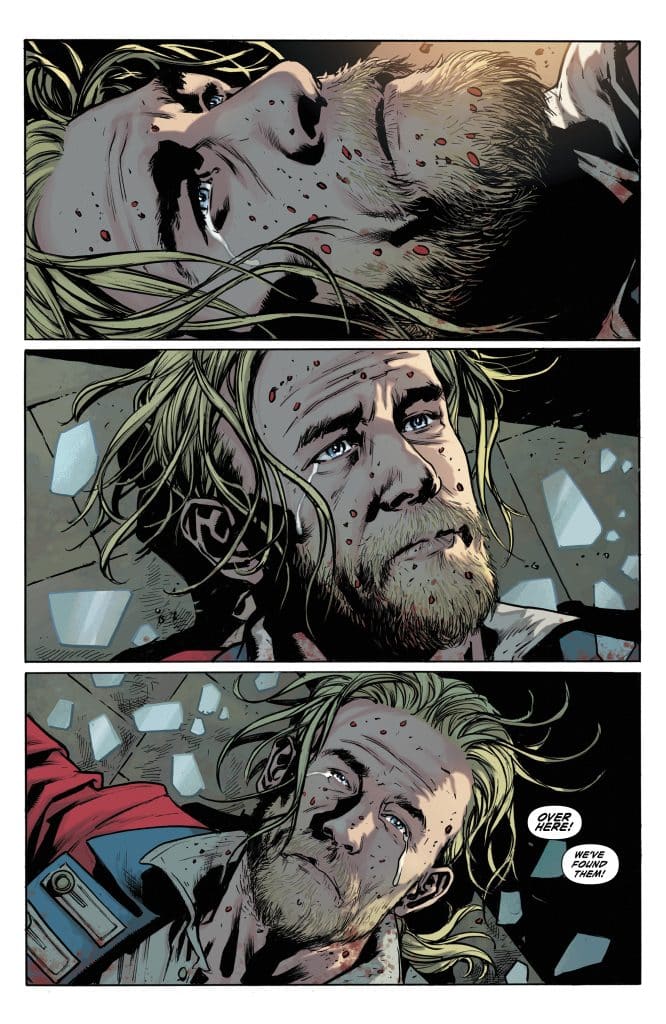 A comic book panel depicting a man with long, disheveled blonde hair and a beard lying on the ground, covered in dirt and blood. His expression is one of distress as he looks upward, with broken glass scattered around him.