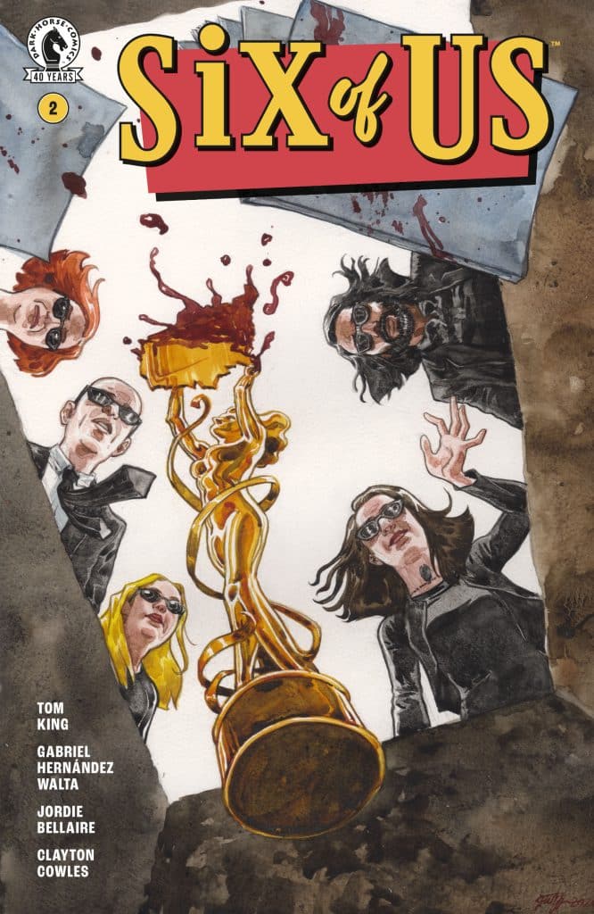 Cover of the comic book 'Six of Us' featuring a group of characters looking down into an abyss. A golden trophy is prominently displayed in the center, surrounded by splashes of red, suggesting a dramatic scene.