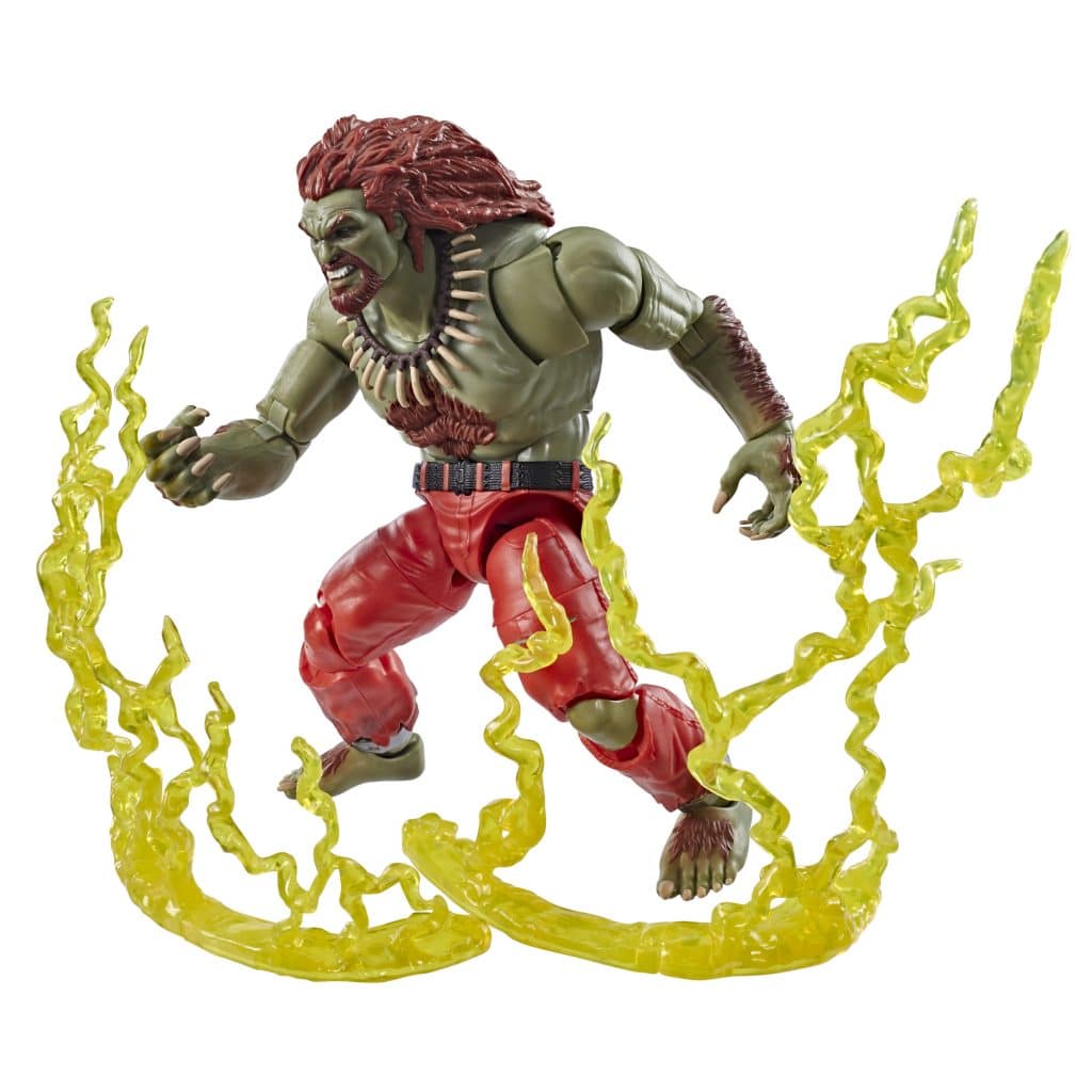 Action figure of a green-skinned character with red hair, wearing red pants and a necklace, standing on a base with yellow energy effects.