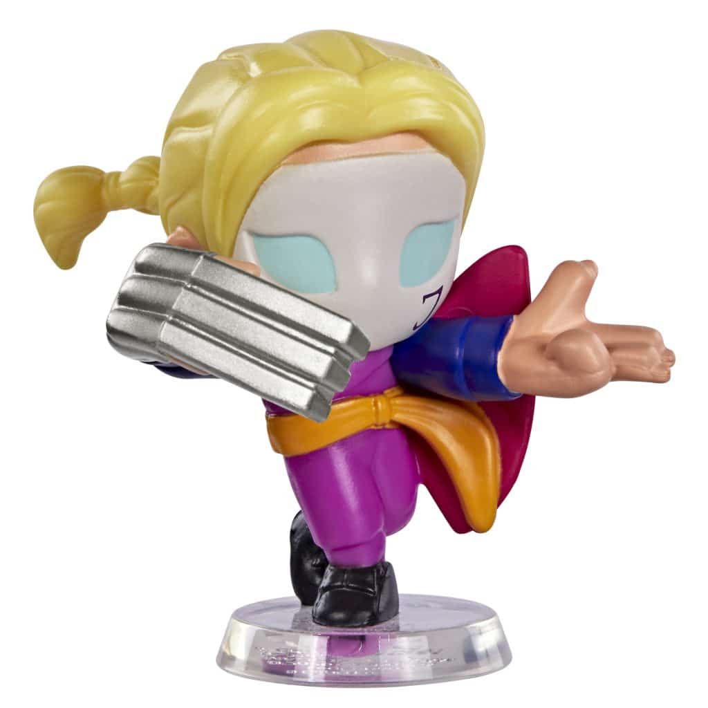 A colorful and playful action figure of a character with blonde hair tied in a ponytail, wearing a purple costume with a red cape and blue sleeves, holding a metallic claw-like weapon.