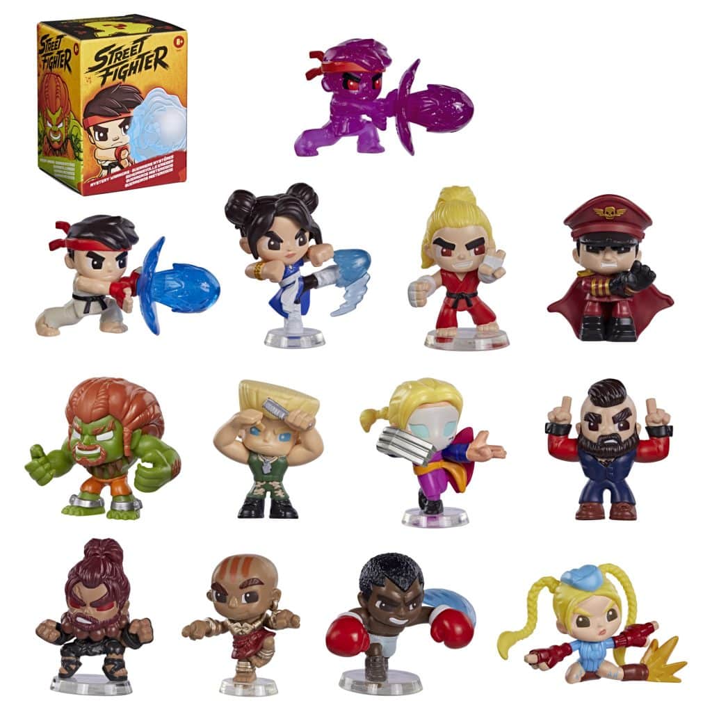 A collection of miniature Street Fighter action figures displayed in various dynamic poses. The figures include iconic characters such as Ryu, Chun-Li, and M. Bison, each showcasing unique features and accessories. The packaging of the toy set is visible in the background.