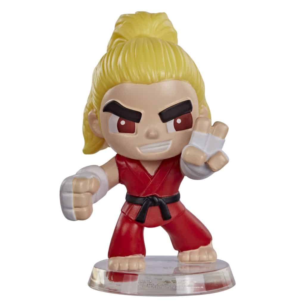 A stylized action figure of a male character with spiky blonde hair, wearing a red martial arts uniform, posed in a fighting stance on a clear display base.
