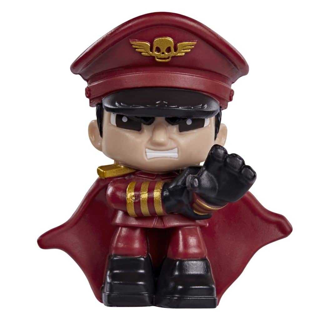 A toy figure of a character in a red military uniform and hat, with a cape, striking a commanding pose.