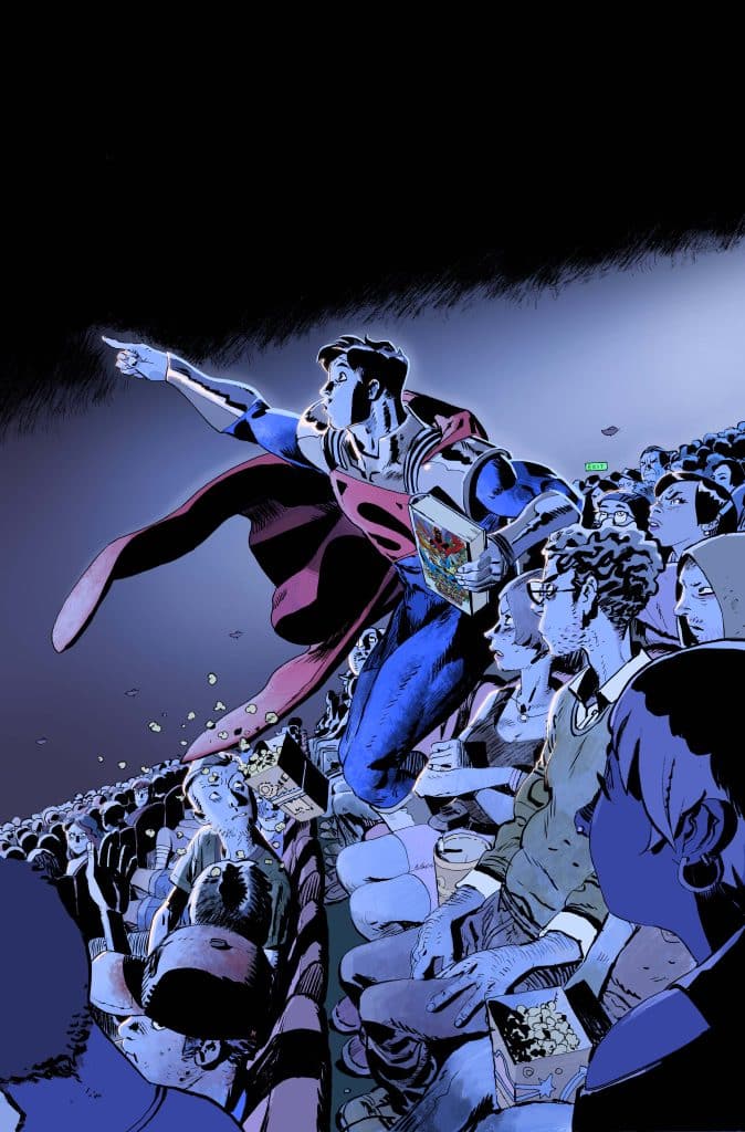 A superhero in a blue costume and red cape stands in a crowded movie theater, pointing excitedly while holding a box of popcorn.
