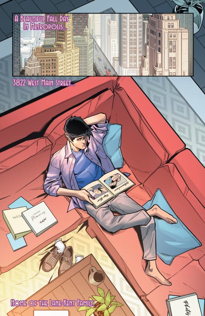 A young man relaxing on a red couch in a cozy living room, reading a scrapbook. The room features a coffee table, plants, and a view of a cityscape through a window, with text indicating it's a fall day in Metropolis.
