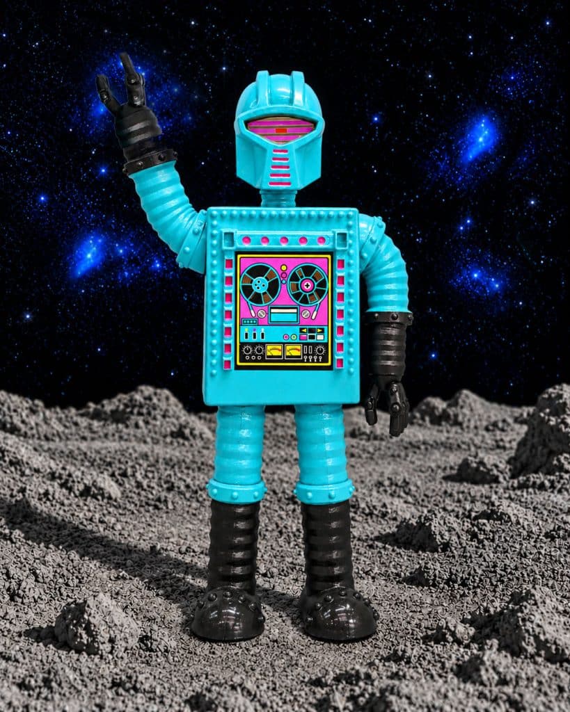 A colorful toy robot with a blue body, black boots, and a playful design, standing on a lunar-like surface with a starry background.