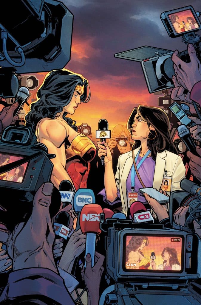 A superhero with long dark hair, wearing a golden tiara and a costume, stands beside a woman in a white lab coat holding a microphone. They are surrounded by a crowd of reporters with cameras, all set against a dramatic sunset backdrop.